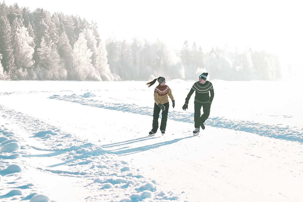 Nainen ja mies luistelee järvenjäälle tehdyllä luisteluradalla.