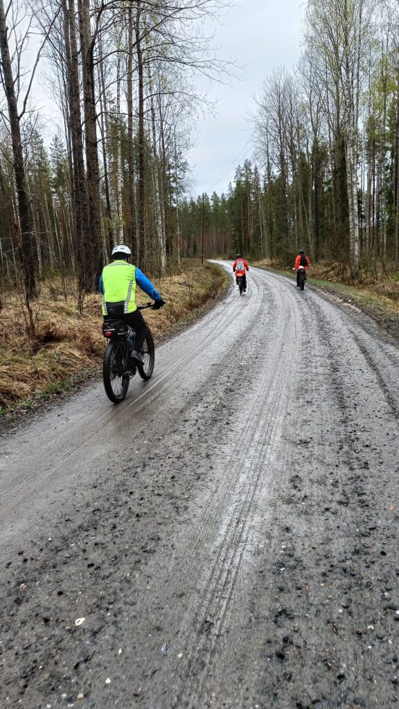 Kolme pyöräilijää soratiellä