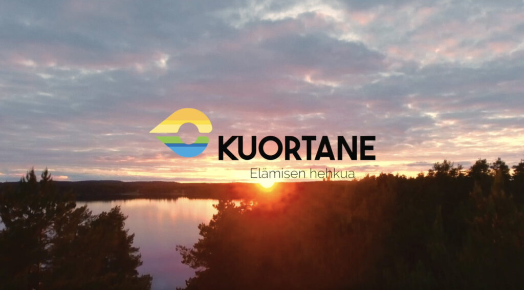 Ilmakuva Kuortaneenjärvestä auringonlaskun aikaan. Kuvan päällä Kuortaneen kunnan logo.