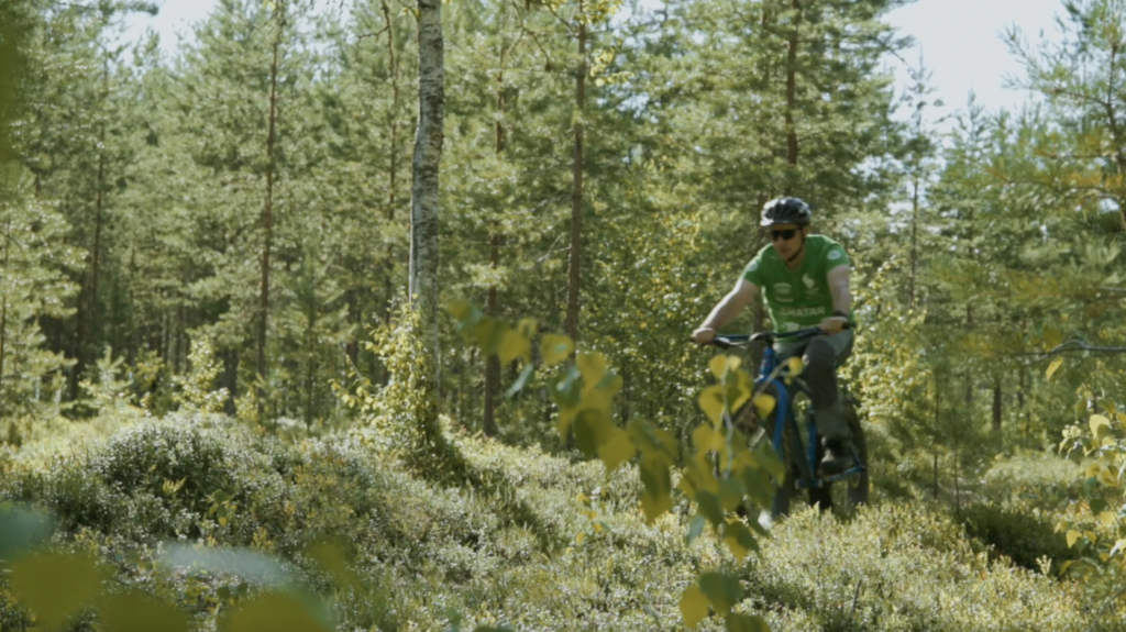Mies maastopyöräilee metsässä.