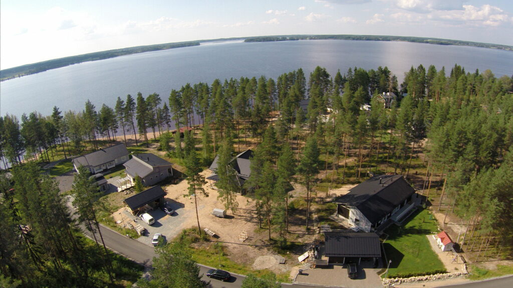 Ilmakuva asuntoalueesta. Kuvassa kolme uutta omakotitaloa. Talojen takana avautuu Kuortaneenjärvi.